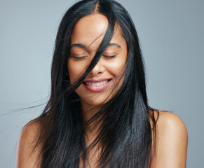 Check out her natural shine. Studio shot of an attractive young woman posing against a grey background.