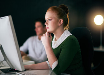 Leinwandbilder - Working hard to make the deadline. Shot of a young businesswoman working on a computer in an office at night.