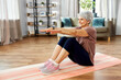 © Syda Productions - sport, fitness and healthy lifestyle concept - smiling senior woman exercising on mat with arms stretched forward at home
