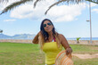portrait of a latin woman smiling, having fun, on vacation in mallorca posing on a warm spring summer day, under a palm tree, hollidays concept