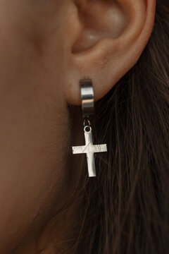 Woman's ear with silver cross earring, macro. Female jewelry and beauty