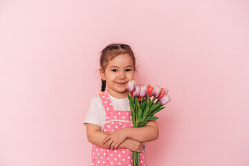 Little Asian girl with bouquet of flowers against pink background. happy mother's day