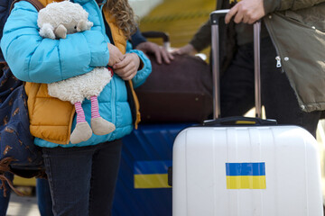 Wall Mural - Close-up of Ukrainian immigrants with luggage waiting at train station, Ukrainian war concept.