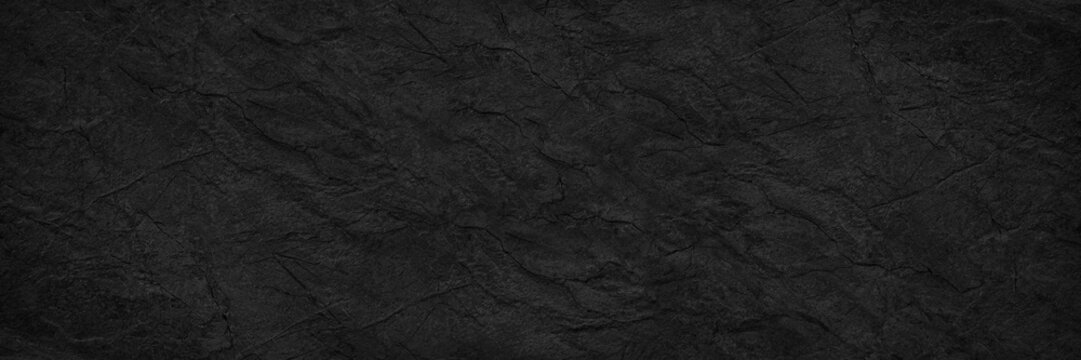 Wall Mural -  - Abstract black background. Wide banner. Dark rock surface texture. Close-up. Stone rough background with copy space for design. Panoramic.