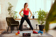 © master1305 - One fitness girl, sportsman doing exercises with sport equipment at home interior, indoors. Concept of sport, fitness, aerobic, sporty lifestyle.