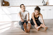 © shunevich - Couple exercising together on the modern kitchen floor. Man and woman in sports wear doing workout at home. Caring girl helping her boyfriend to do stretching
