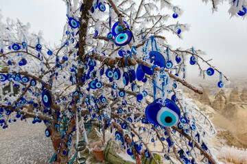 Wall Mural - Blue evil eye ;nazar boncugu, turkish symbols hanging on a tree. cappadocia