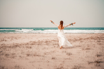 Wall Mural - Model in boho style in a white long dress and silver jewelry on the beach. Her hair is braided, and there are many bracelets on her arms.