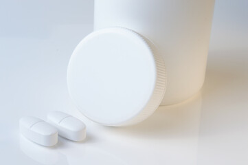 Wall Mural - white plastic medicine jar and two white pills. light background