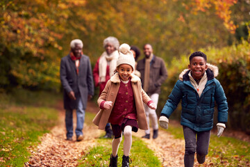 Wall Mural - Smiling Multi-Generation Family Having Fun Walking Through Autumn Countryside Together