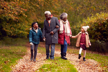 Wall Mural - Grandparents Holding Hands With Grandchildren On Walk Through Autumn Countryside Together