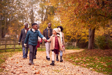 Wall Mural - Smiling Multi-Generation Family Having Fun Walking Through Autumn Countryside Together