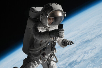 Wall Mural - female astronaut having a video call on her phone while performing spacewalk in open space, earth in