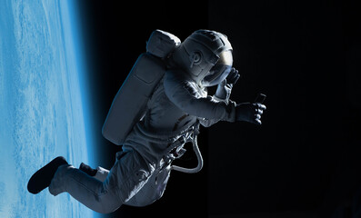 Wall Mural - female astronaut having a video call on her phone while performing spacewalk in open space, earth in