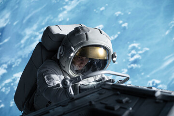 Wall Mural - female astronaut performing spacewalk, working on a outer part of a space craft