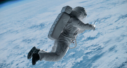 Wall Mural - female astronaut having a video call on her phone while performing spacewalk in space, earth in the 
