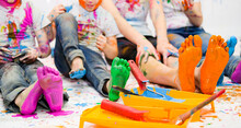 Children Paint Together With Bright Colors And Their Feet And Faces Are Stained With Paint. . High Quality Photo