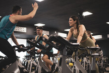 People On Bikes In Spinning Class In Modern Gym, Exercising On Stationary Bike. Group Of Athletes Training On Exercise Bike