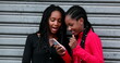 © Marco - Two black girl friends laughing using smartphone together