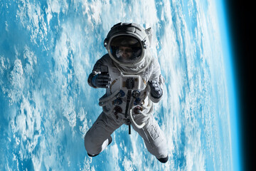 Wall Mural - female astronaut having a video call on her phone while performing spacewalk in deep space, earth in