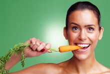 Smiling Young Woman Eating Carrot Against Green Background. Closeup Portrait Of A Smiling Young Woman Eating Carrot Against Green Background.