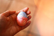Woman's hand holding decorated Easter egg with cracked shield