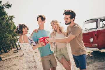 Photo of four best friends enjoy cheering beer toast road trip concept wear casual outfit nature seaside beach outside