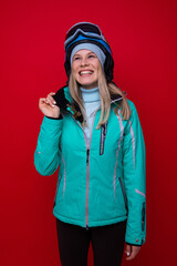 Wall Mural - Portrait of a smiling young woman in a jacket, helmet and ski goggles