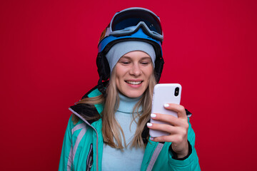 Wall Mural - A young female snowboarder types on her phone on a red background