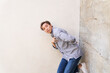 Man dancing posing by textured concrete wall
