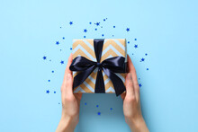 Female Hands Holding Vintage Gift Box With Blue Ribbon Bow On Pastel Blue Background With Confetti. Happy Fathers Day, Birthday Concept.