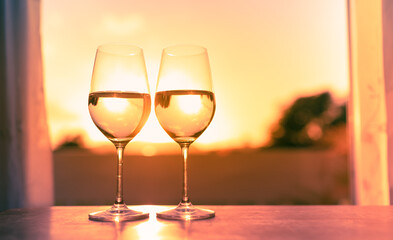 Wall Mural - Pair of wine glasses on a bar at sunset 