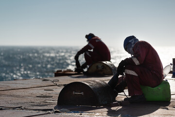 Wall Mural - Seaman ship crew working on deck cutting with flex machine grinder after carriage of cargo.