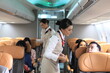 © sittinan - air  hostess service on plane , flight attendant checking and closing cabin compartment in airplane