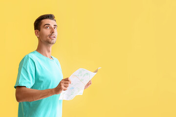 Wall Mural - Young male tourist with map on color background