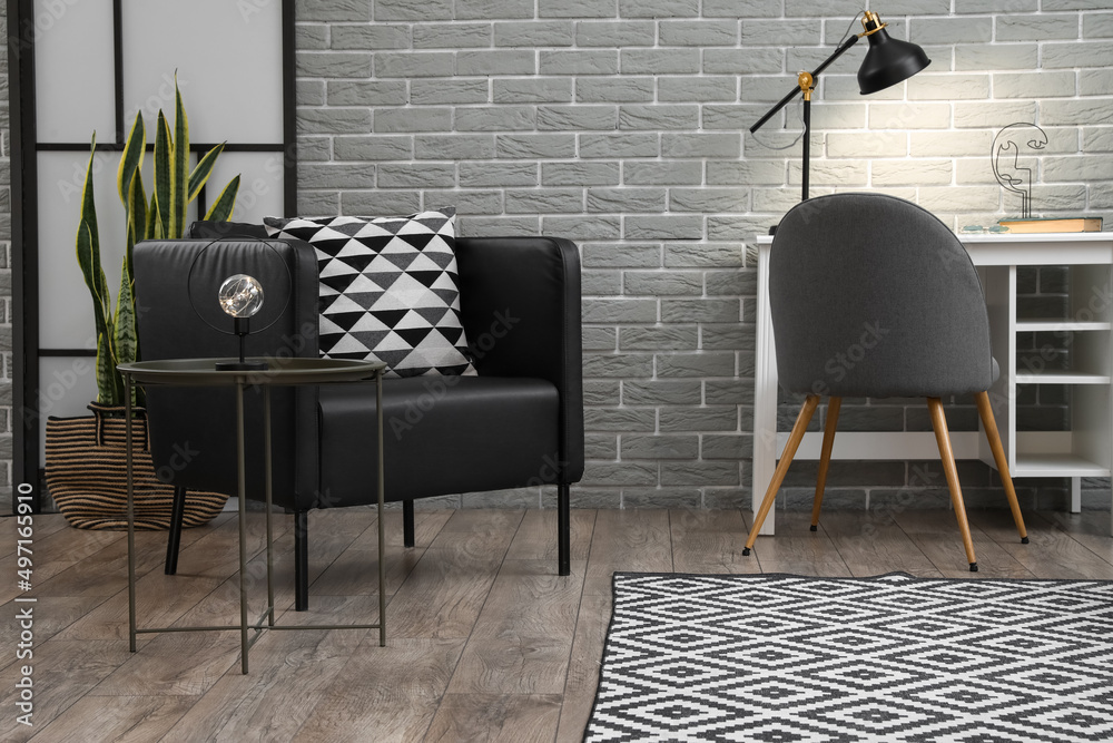 Black armchair, table with lamp and modern workplace in living room