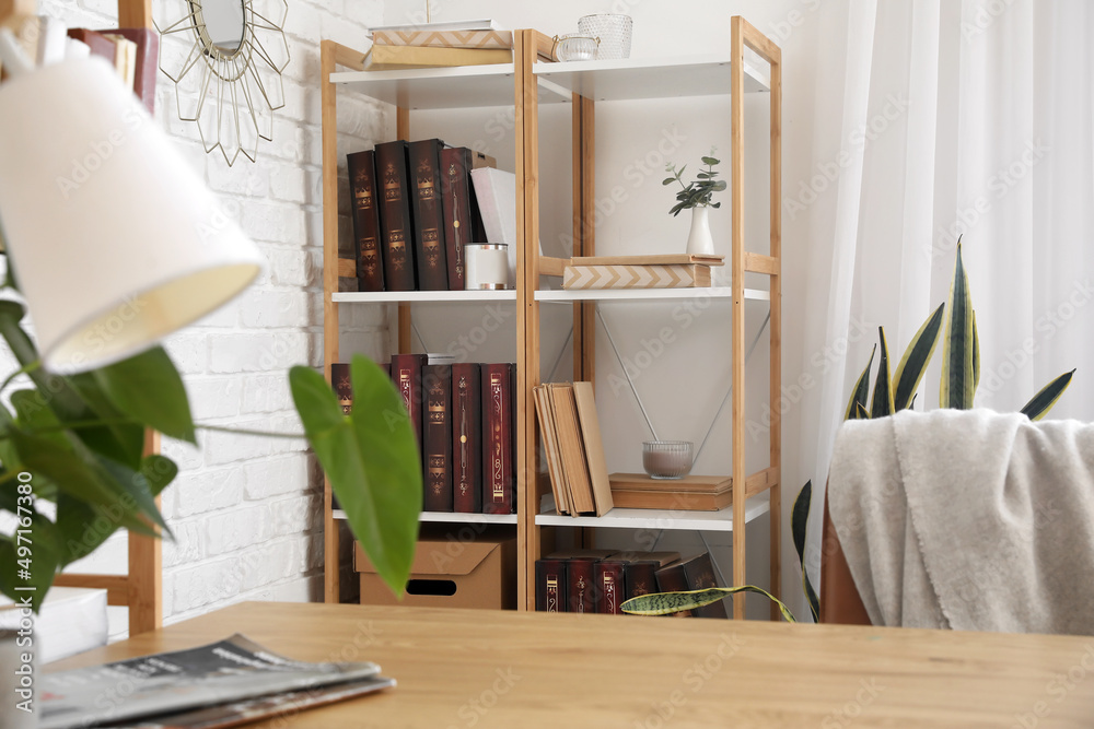 Wooden bookcase with candles and eucalyptus near light wall in office