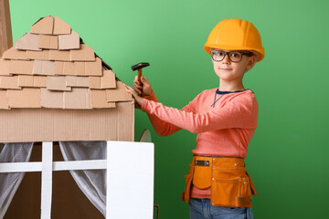 Poster - Funny little builder playing with cardboard house on color background