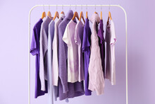 Rack With Clothes In Purple Shades On Lilac Background