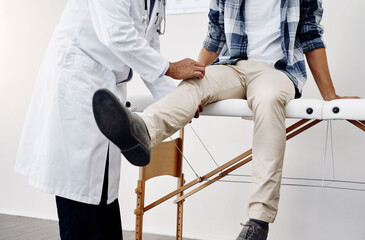 Wall Mural - Is there any pain here. Cropped shot of an unrecognizable male doctor doing a check up on a young patient whos seated on a doctors bed.