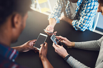 Poster - Working hands-on with technology. Cropped shot of three people sitting around a table together and using their cellphones.