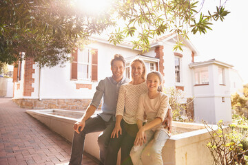 Sticker - A place to call home. A portrait of a happy family sitting outside of their home.