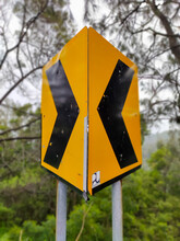 Dangerous Turn Left And Turn Right Sign, Yellow Black Road Sign Mounted On Roadside Against Blurred Background