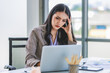 © Bangkok Click Studio - Asian young unhappy upset stressed depressed frowning face female businesswoman employee staff in formal business suit sitting at working desk holding hands on head having problem trouble headache