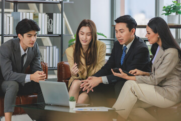 Group of millennial Asian young happy male female businessman businesswoman employee staff in formal business suit sitting on leather sofa smiling discussing brainstorming talking together in office