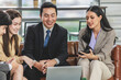 © Bangkok Click Studio - Group of millennial Asian young happy male female businessman businesswoman employee staff in formal business suit sitting on leather sofa smiling discussing brainstorming talking together in office