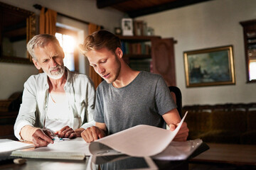 This is what I need your help with. Shot of two men working on a project together at home.