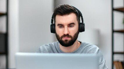 Closeup confident man in headphones working use laptop browsing internet talking online video call