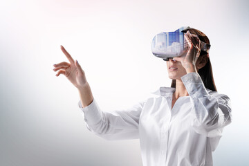 Poster - Attractive young european woman with VR glasses pointing at abstract light white city background. Virtual reality and experience concept. Double exposure.