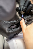 Fototapeta Konie - Manicure master uses electric nail file machine in a nail salon, close up